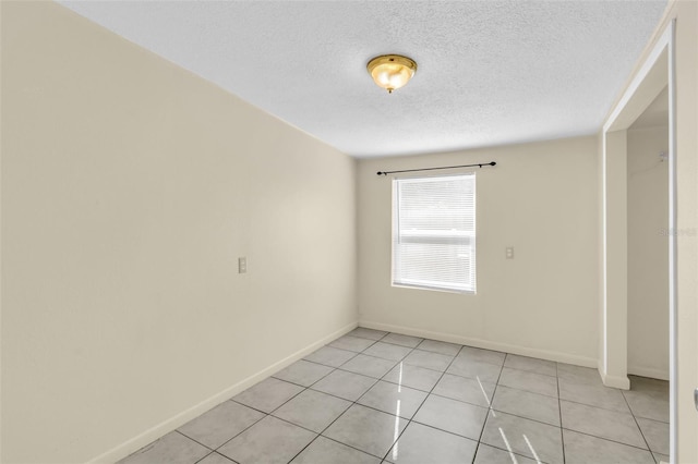 tiled empty room featuring a textured ceiling