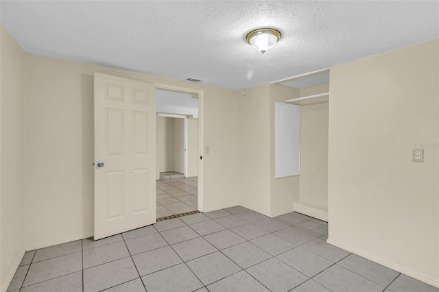 spare room with light tile patterned flooring and a textured ceiling