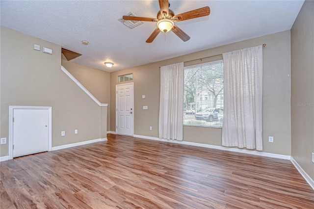 unfurnished living room featuring ceiling fan, light wood-type flooring, and a textured ceiling