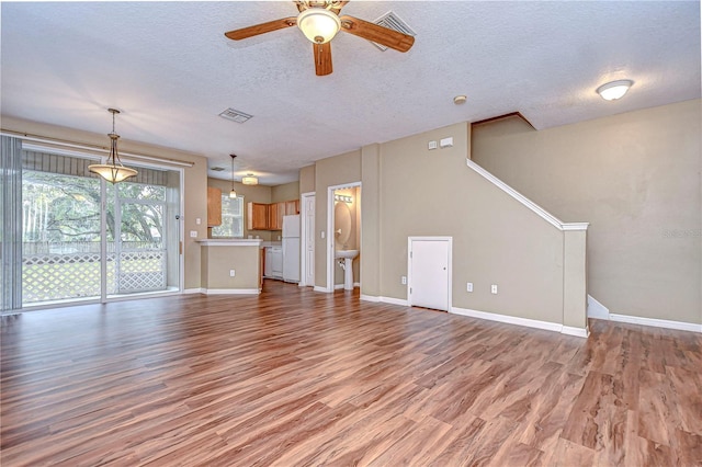 unfurnished living room with hardwood / wood-style flooring, ceiling fan, and a textured ceiling