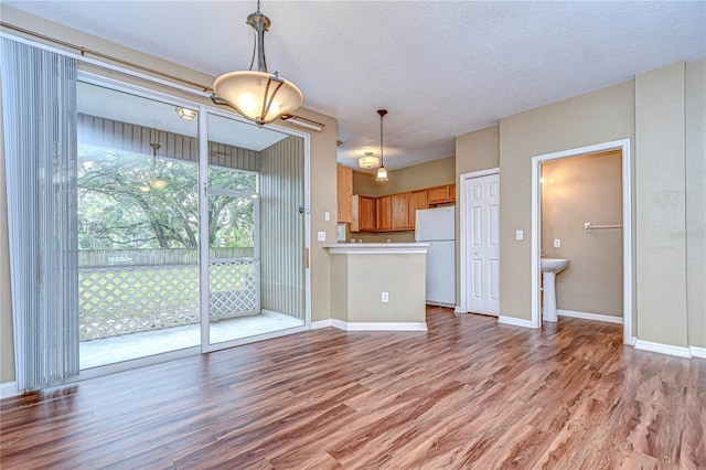 interior space with kitchen peninsula, hardwood / wood-style floors, white fridge, and a textured ceiling