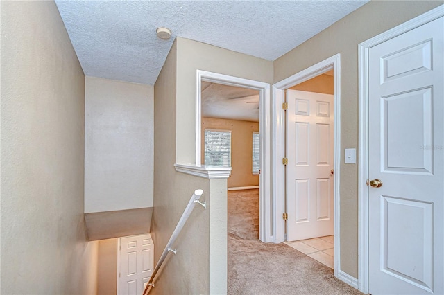 hall with light carpet and a textured ceiling