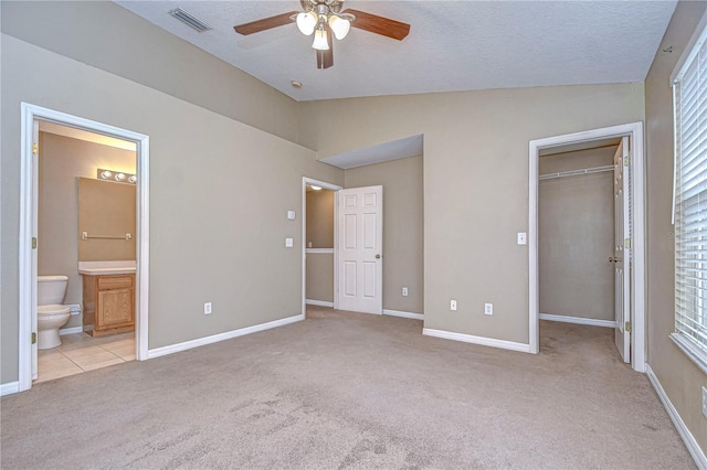 unfurnished bedroom featuring light colored carpet, vaulted ceiling, ceiling fan, connected bathroom, and a closet