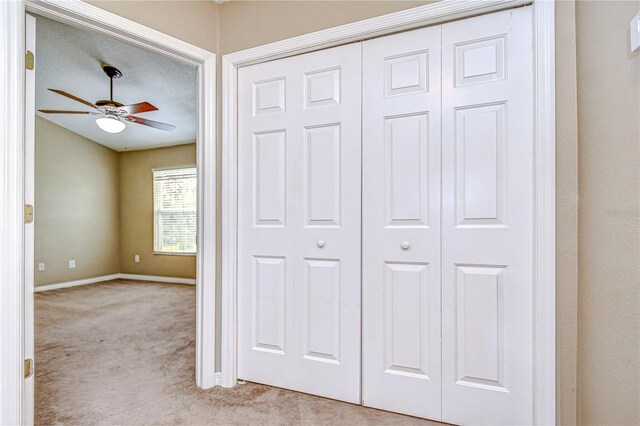 hallway with a textured ceiling and light colored carpet