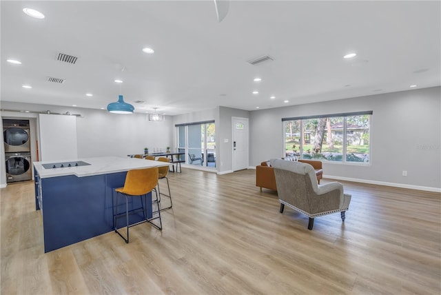 living room with light hardwood / wood-style floors and stacked washer and clothes dryer