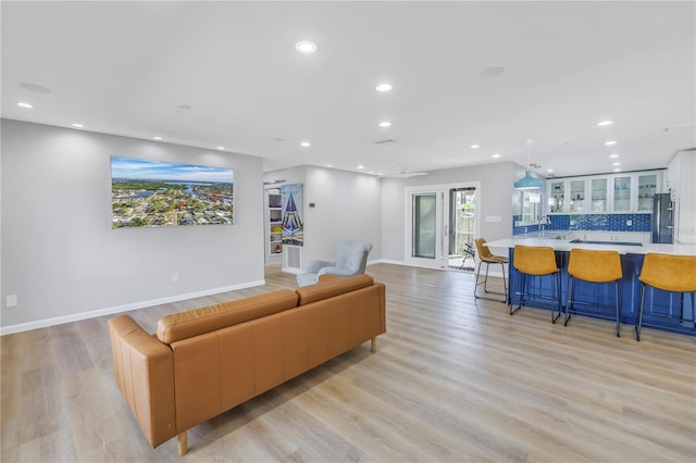 living room featuring ceiling fan, sink, and light hardwood / wood-style flooring