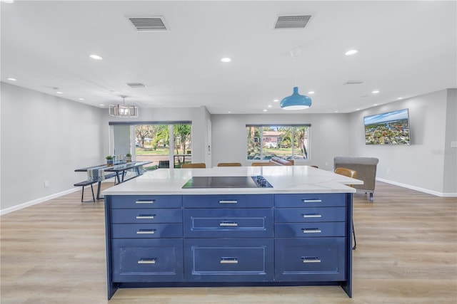 kitchen featuring black electric cooktop, a kitchen island, pendant lighting, and light hardwood / wood-style floors