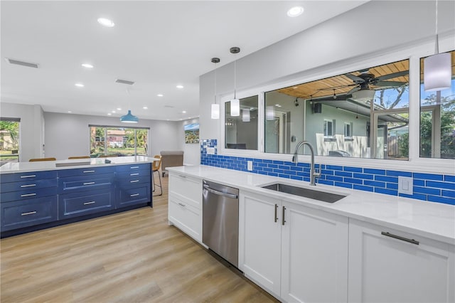 kitchen featuring tasteful backsplash, stainless steel dishwasher, sink, pendant lighting, and white cabinets