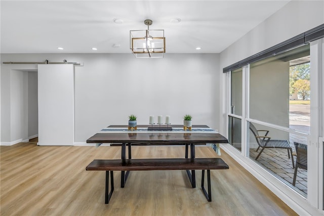 dining room featuring a chandelier, a barn door, and light hardwood / wood-style floors