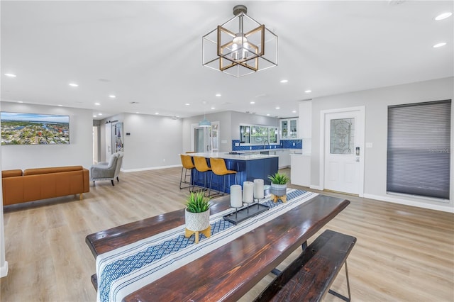 dining space featuring light wood-type flooring, sink, and an inviting chandelier