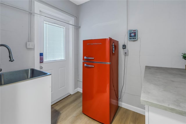 kitchen featuring stainless steel refrigerator, light hardwood / wood-style flooring, and sink