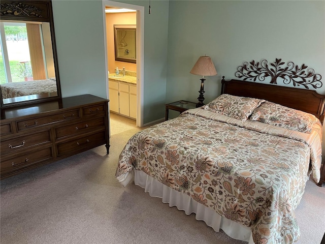 carpeted bedroom featuring ensuite bath and sink