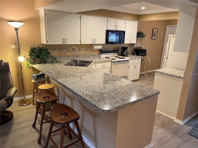 kitchen with kitchen peninsula, white cabinetry, sink, and white appliances