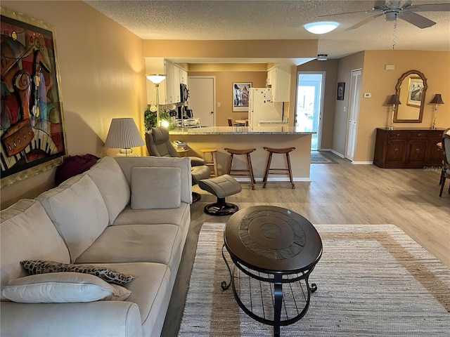 living room featuring a textured ceiling, light hardwood / wood-style floors, ceiling fan, and sink