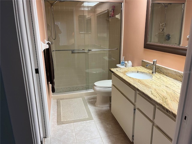 bathroom with tile patterned floors, vanity, toilet, and a shower with door