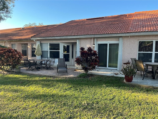 rear view of property with a patio and a lawn