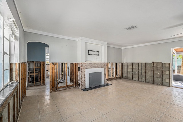 unfurnished living room with ceiling fan and crown molding