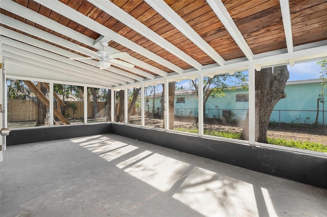 unfurnished sunroom with vaulted ceiling with beams, a healthy amount of sunlight, wooden ceiling, and ceiling fan