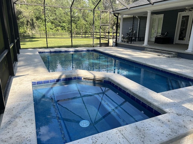 view of swimming pool featuring a lawn, a patio area, ceiling fan, and glass enclosure