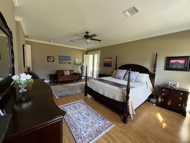 bedroom with ceiling fan, light hardwood / wood-style flooring, a textured ceiling, and ornamental molding