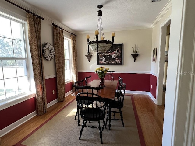 dining area featuring hardwood / wood-style floors, crown molding, and a notable chandelier