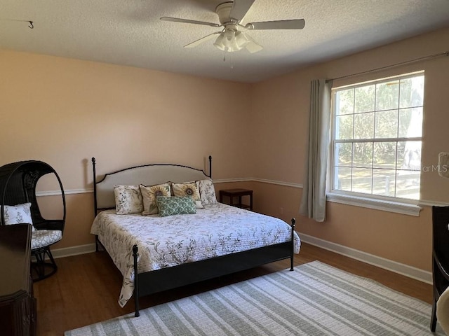 bedroom with ceiling fan, wood-type flooring, and a textured ceiling