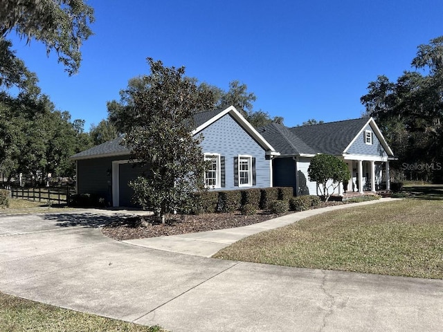 view of front facade with covered porch, a front yard, and a garage