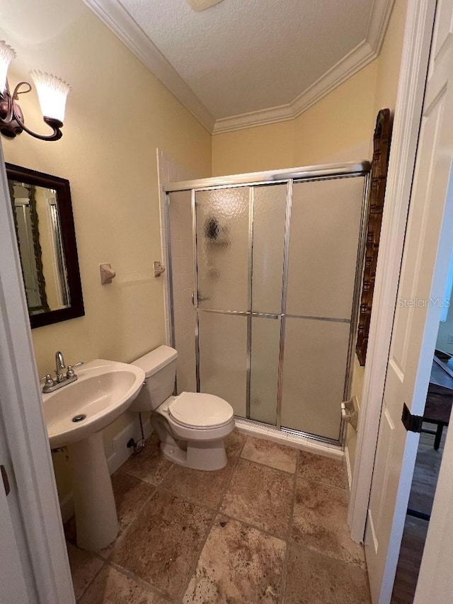 bathroom with a textured ceiling, toilet, crown molding, and walk in shower