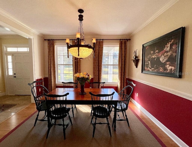 dining space featuring wood-type flooring, crown molding, and a notable chandelier