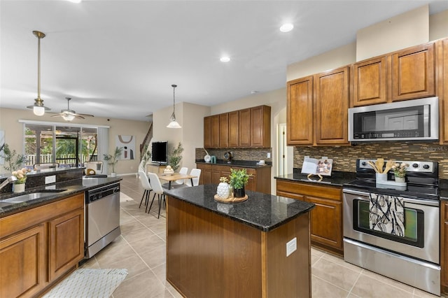 kitchen with appliances with stainless steel finishes, ceiling fan, light tile patterned floors, pendant lighting, and a kitchen island