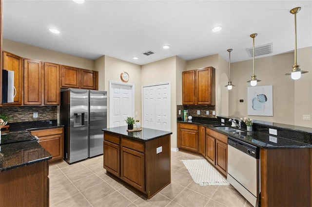 kitchen with backsplash, hanging light fixtures, appliances with stainless steel finishes, and dark stone counters