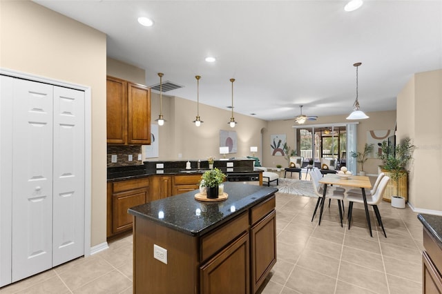 kitchen featuring ceiling fan, a center island, light tile patterned floors, and decorative light fixtures