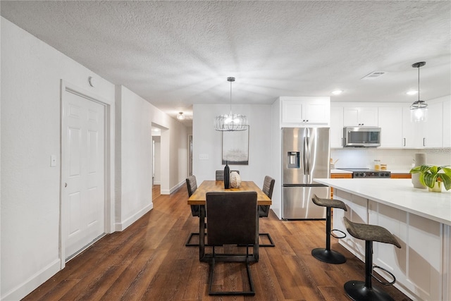 dining space featuring a textured ceiling, dark wood-type flooring, and an inviting chandelier