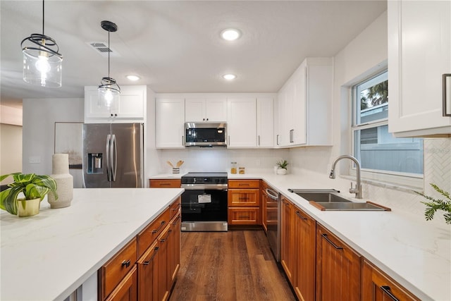 kitchen featuring sink, tasteful backsplash, decorative light fixtures, white cabinets, and appliances with stainless steel finishes