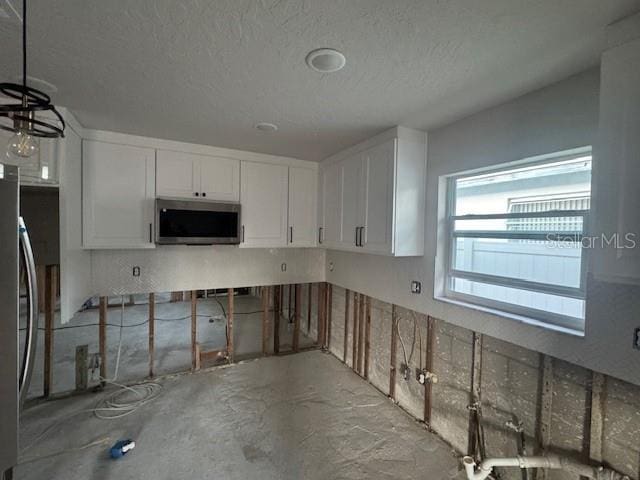 kitchen with a textured ceiling, white cabinetry, and stainless steel appliances