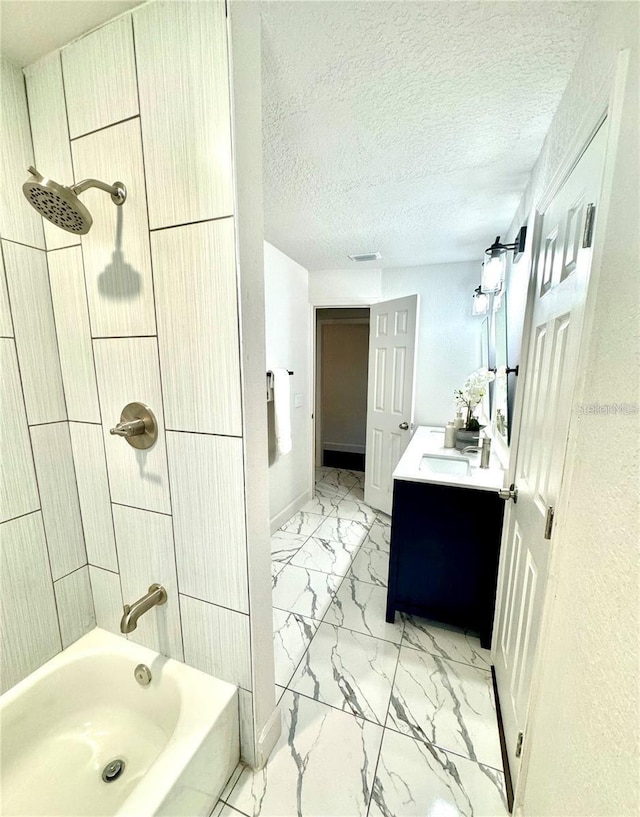 bathroom with a textured ceiling, vanity, and shower / washtub combination