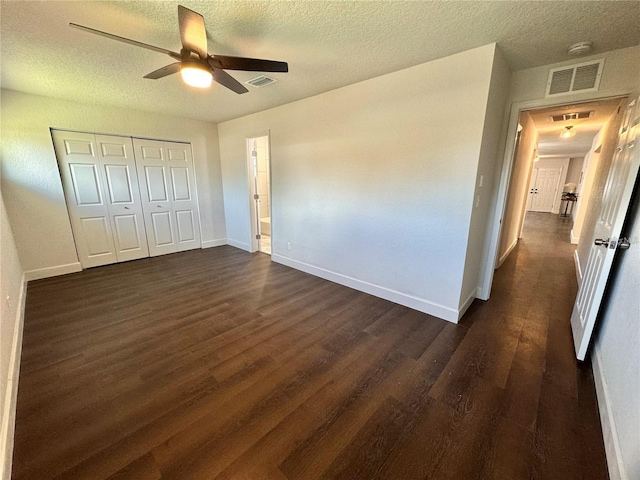 unfurnished bedroom with ceiling fan, dark hardwood / wood-style floors, a textured ceiling, and a closet