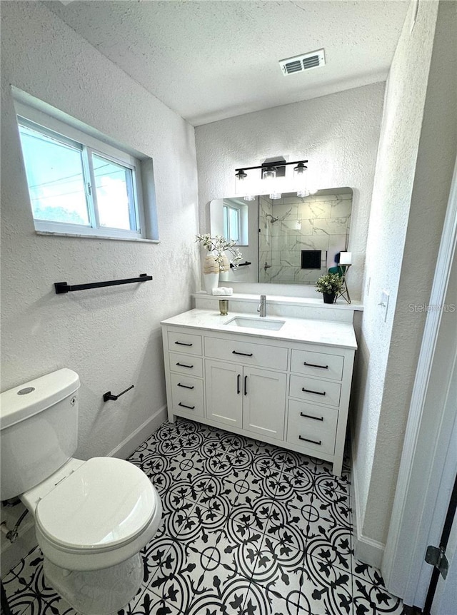 bathroom featuring vanity, tile patterned floors, a textured ceiling, and toilet