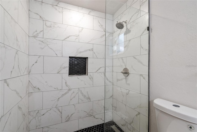 bathroom featuring toilet and tiled shower