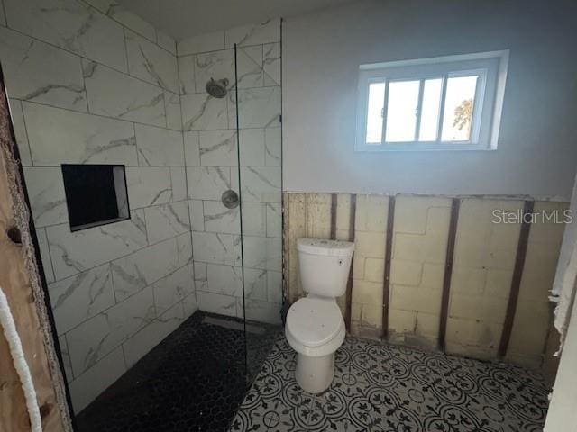 bathroom featuring tile patterned floors, toilet, and a tile shower