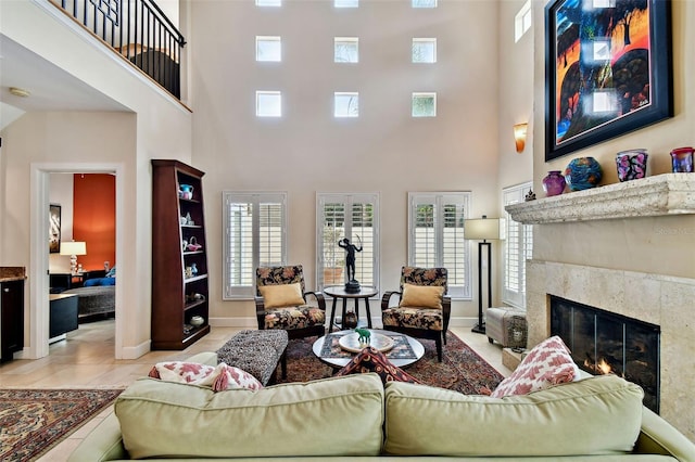 living room featuring a high ceiling, plenty of natural light, and a tiled fireplace