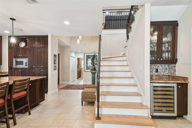 stairs featuring bar, tile patterned flooring, and beverage cooler