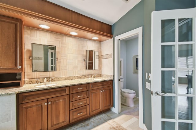 bathroom with toilet, vanity, and backsplash