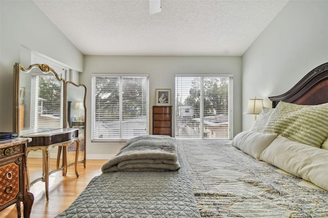 bedroom with ceiling fan, a textured ceiling, and light hardwood / wood-style flooring