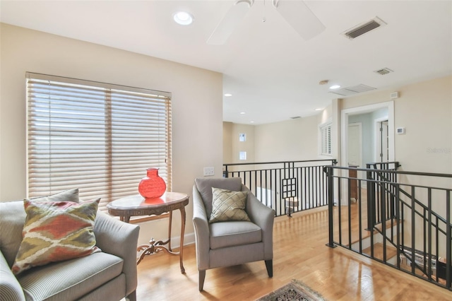 living area with ceiling fan and light hardwood / wood-style flooring