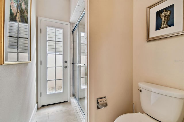 bathroom featuring toilet, tile patterned floors, and a shower with shower door