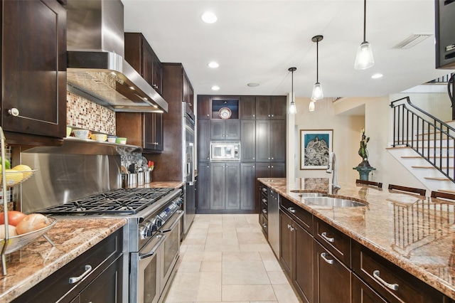 kitchen with wall chimney range hood, sink, hanging light fixtures, premium appliances, and light stone countertops