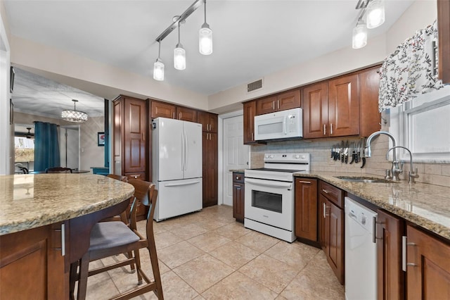 kitchen featuring light stone countertops, pendant lighting, white appliances, and sink