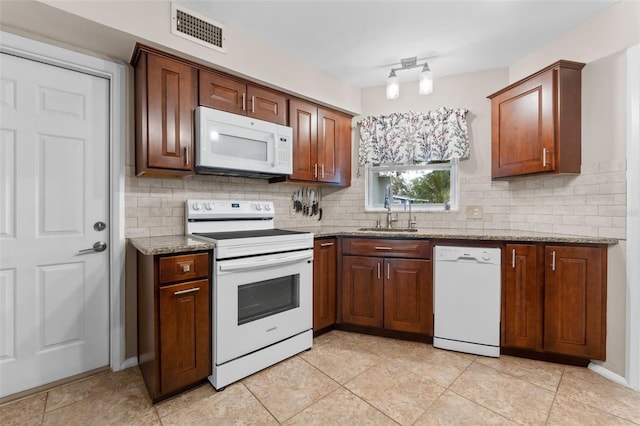 kitchen with decorative backsplash, light stone countertops, white appliances, and sink