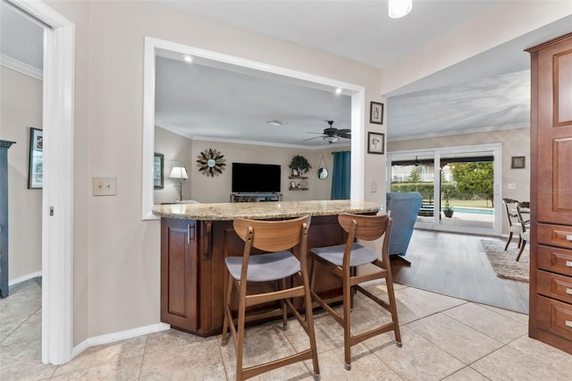 bar featuring light stone countertops, light tile patterned floors, ceiling fan, and ornamental molding